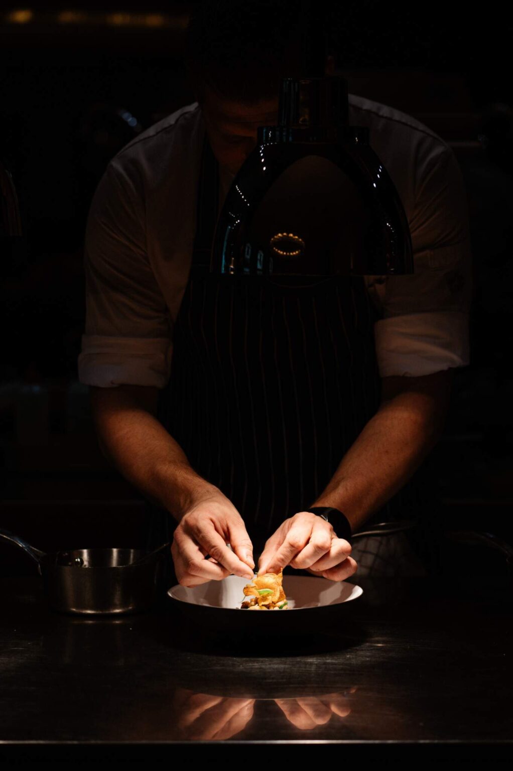 Chef die een gerecht opmaakt in de open keuken van Harry’s
